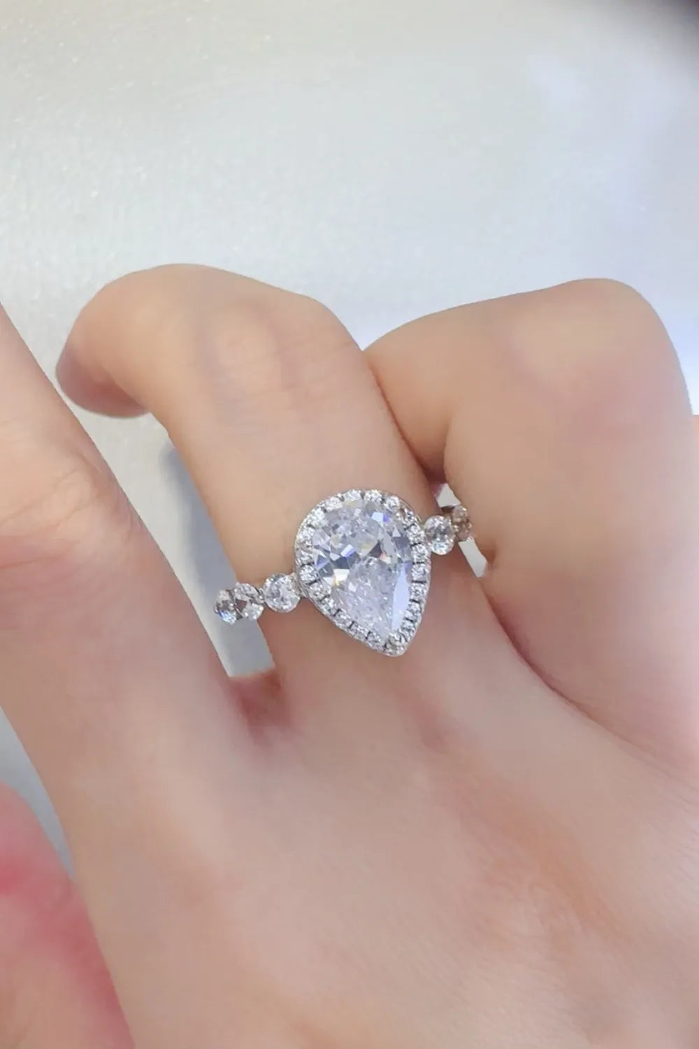 Silver pear-cut halo moissanite ring with accent stones on band