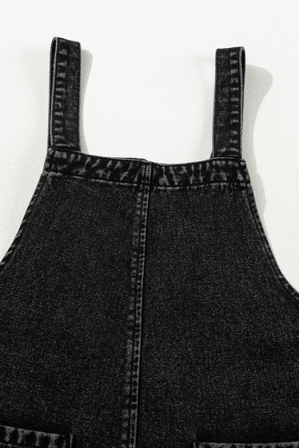Black denim culotte overalls with distressed details and adjustable straps.