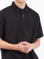 Black textured performance polo shirt with a classic collar and two-button placket.