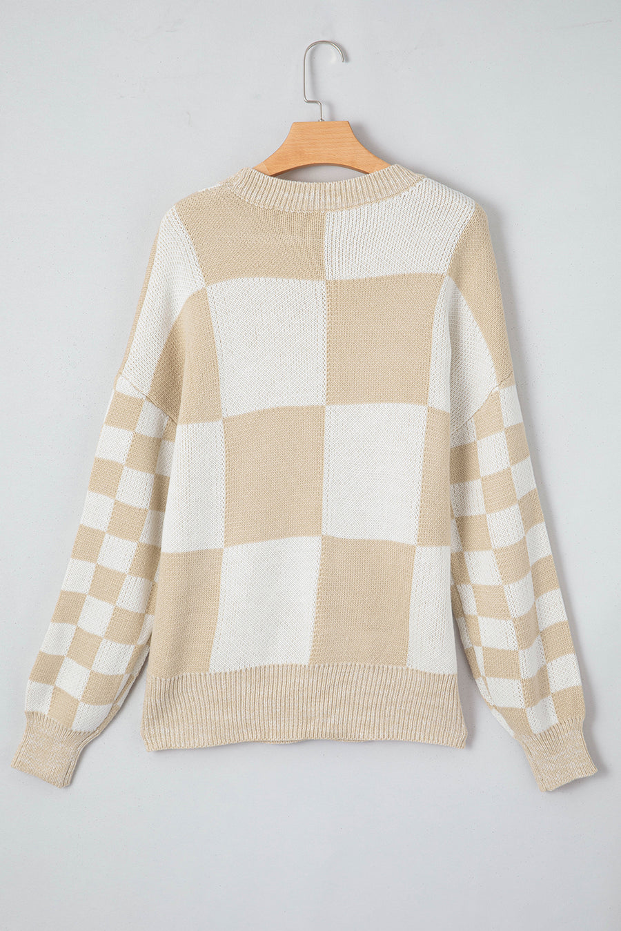 Beige and white checkerboard knit sweater with crewneck and long sleeves.