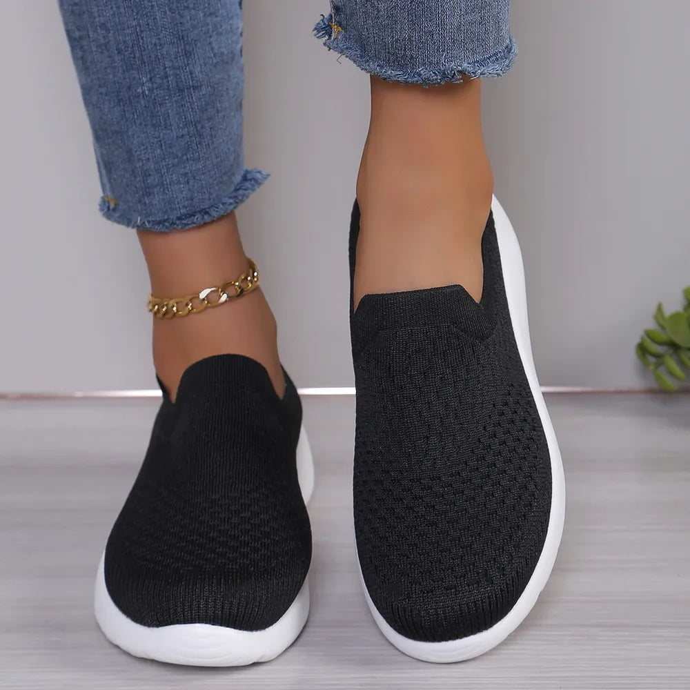 Black knit slip-on sneakers with white sculpted sole and airflow design.