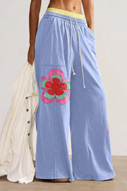 Maternity wide-leg pants in light blue cotton with a flower applique and drawstring waist.
