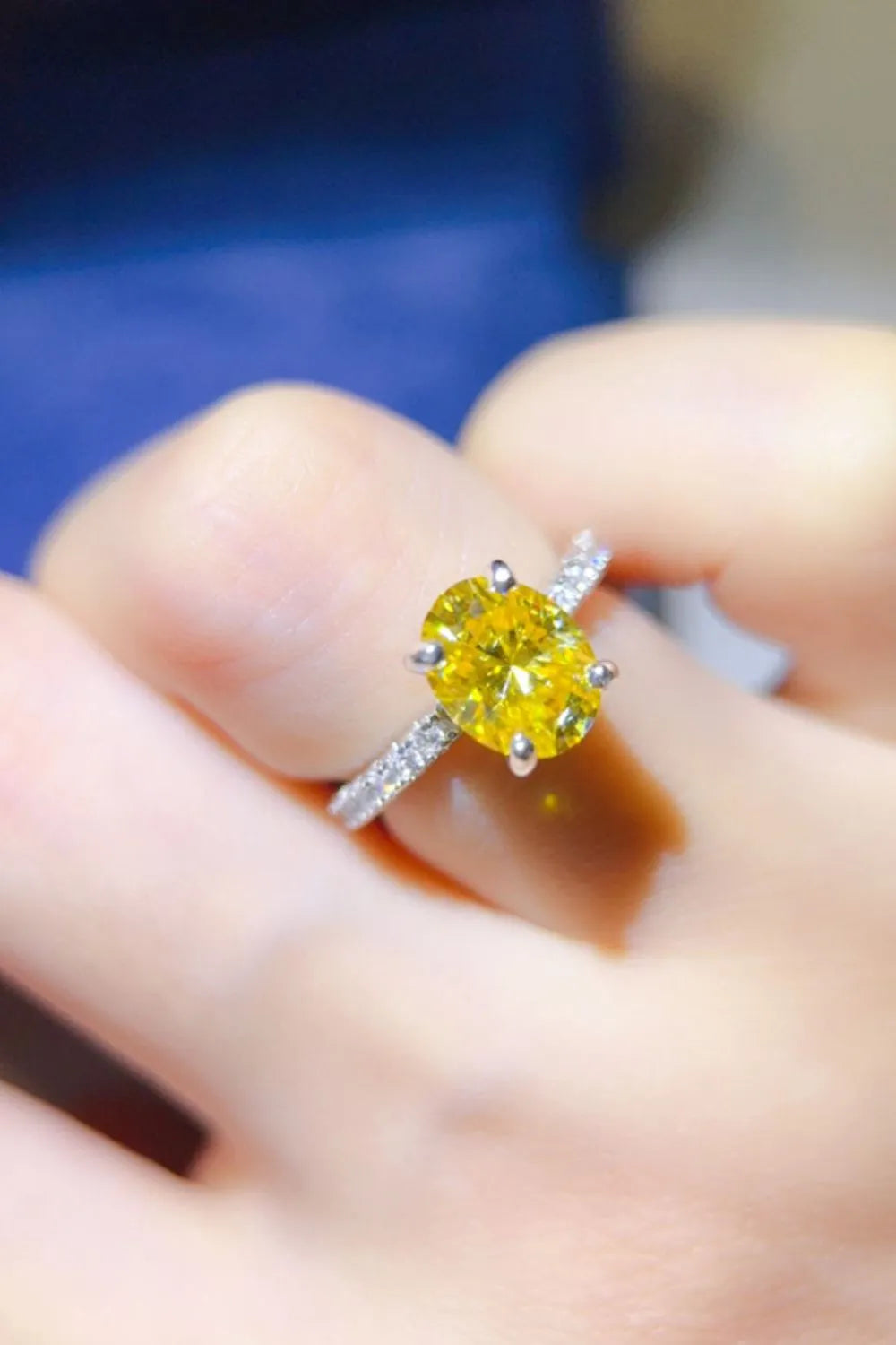 Radiant yellow oval moissanite ring with diamond band on finger