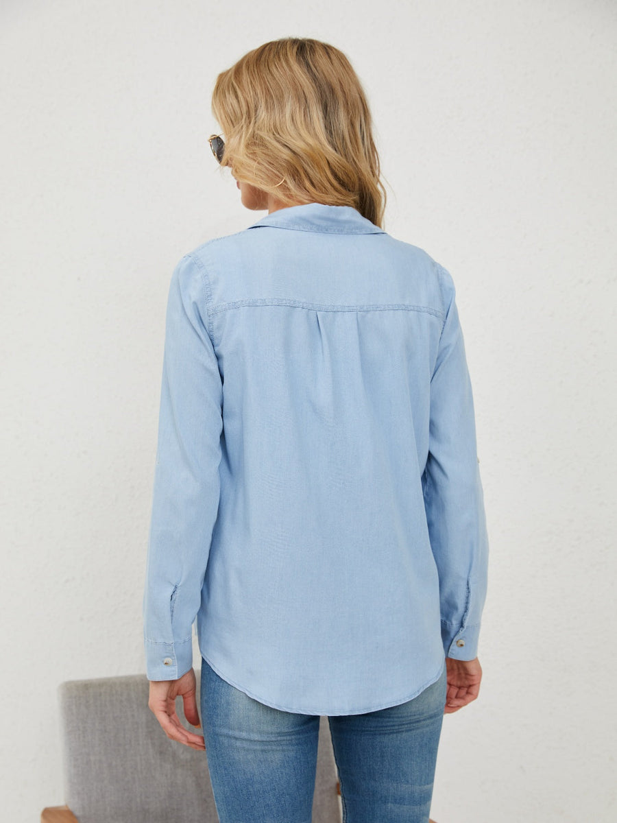 Light wash denim utility shirt with button cuffs and a curved hem.