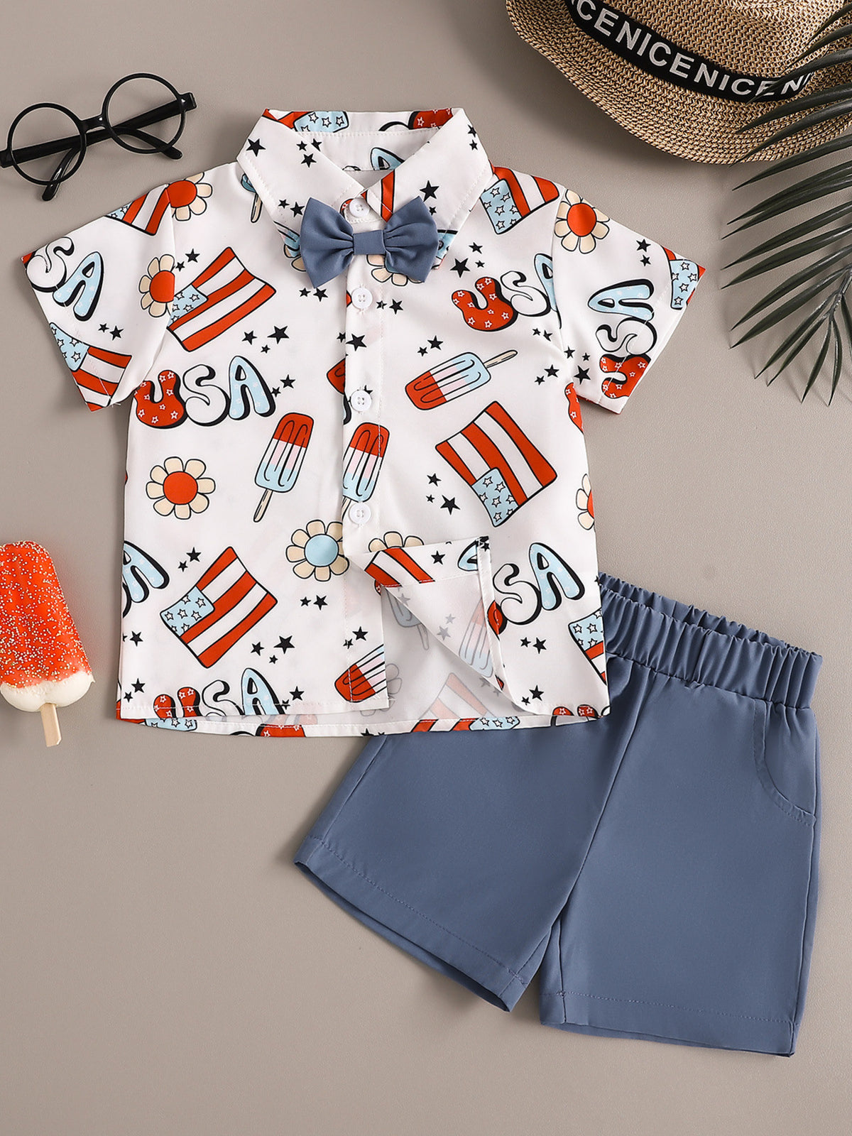 Toddler boys' patriotic print short sleeve shirt with bow tie and blue shorts.