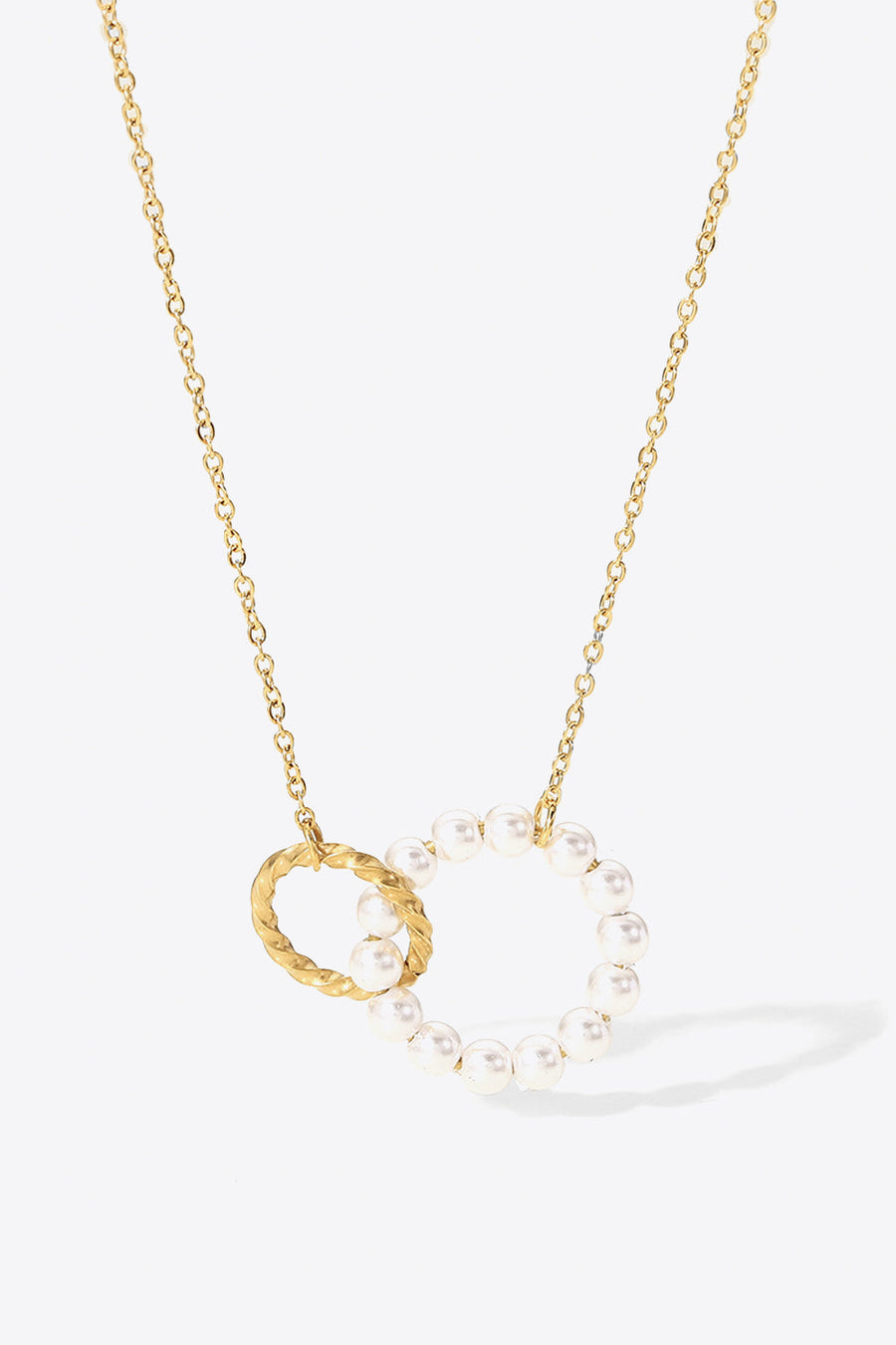 Interlocking pearl and gold-plated circle pendant necklace with a twisted gold ring detail.
