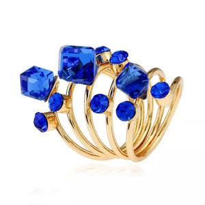 Gold-plated ring with royal blue crystals in various shapes and sizes, multi-layered design.