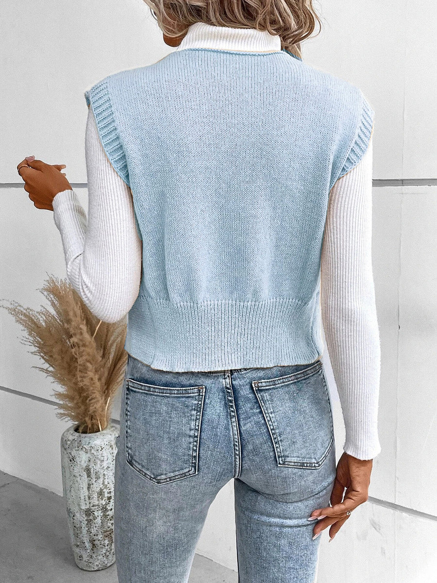 Light blue knit vest with ribbed trim and crew neck, worn over a white turtleneck.