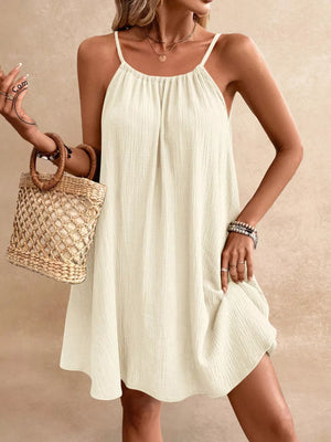 Cream spaghetti strap gauze dress with gathered neckline and A-line skirt.