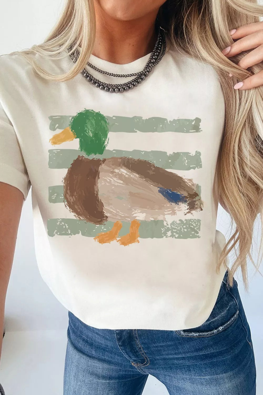 Cream cotton t-shirt with artistic mallard duck graphic and green brushstroke stripes.