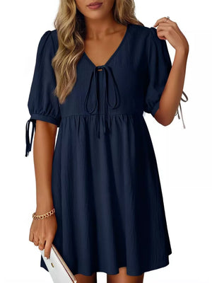 Navy mini dress with tie neck, puff sleeves, and tie cuffs.