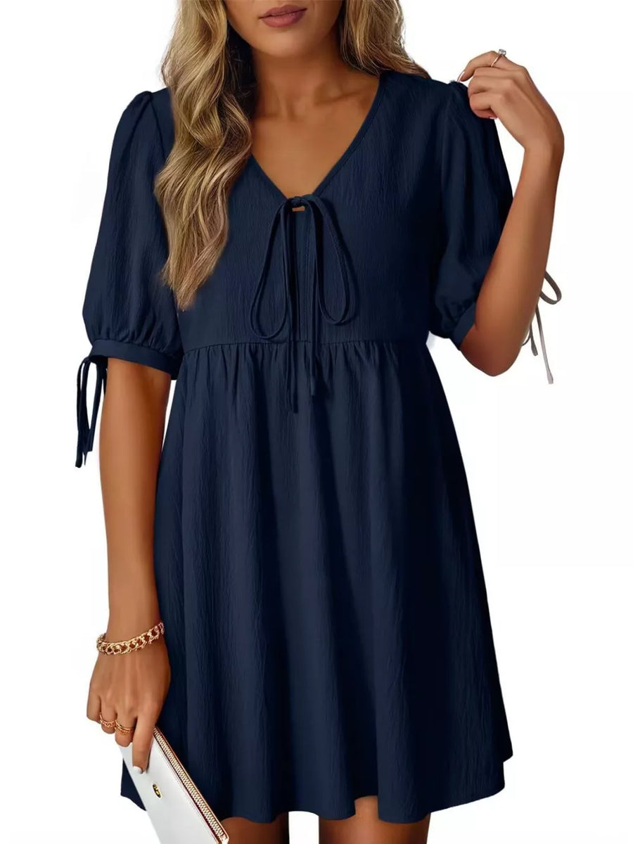 Navy mini dress with tie neck, puff sleeves, and tie cuffs.