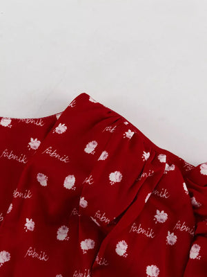 Red floral print blouse with script text detail and ruffled neckline