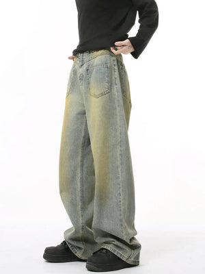Distressed denim jeans in a medium wash with a relaxed fit and yellowed accents.
