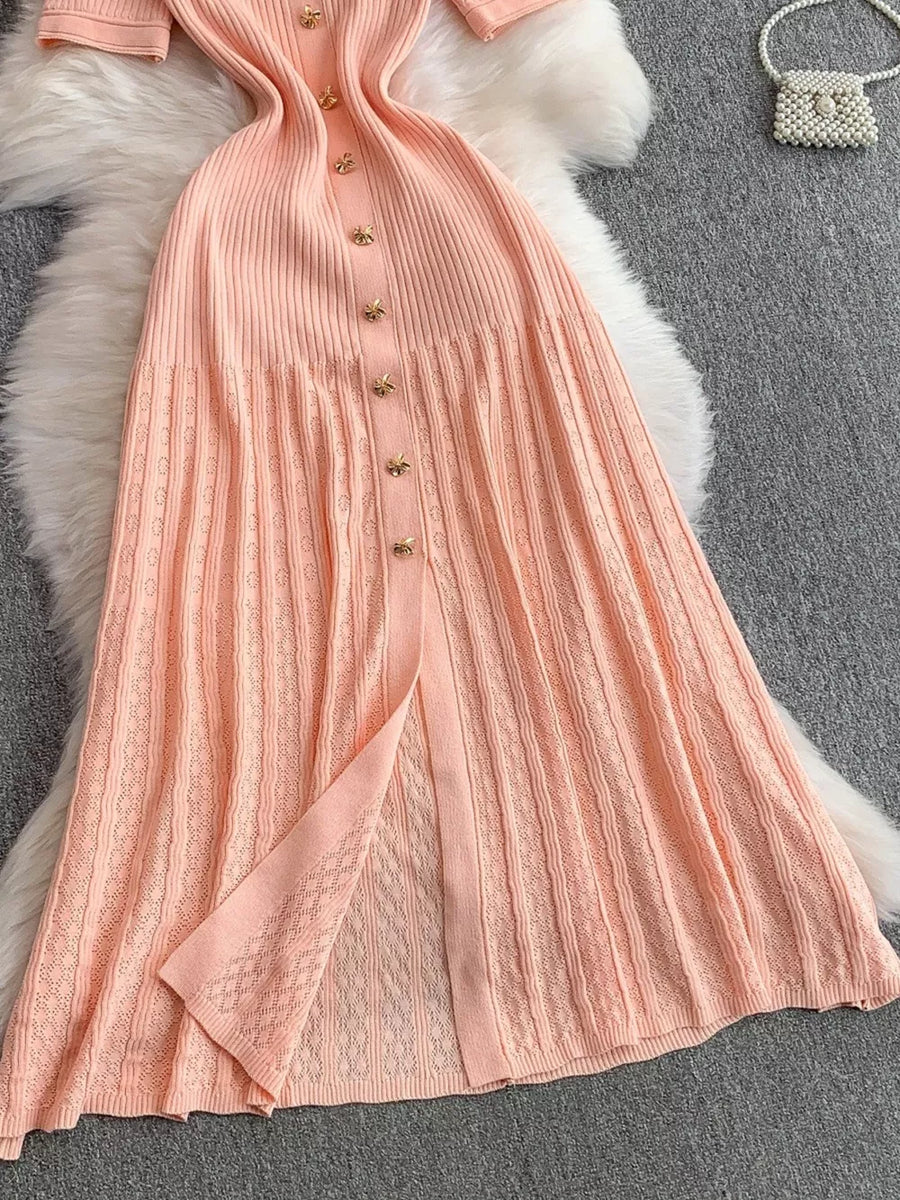Pink ribbed knit midi dress with gold button detail and open knit skirt panel.