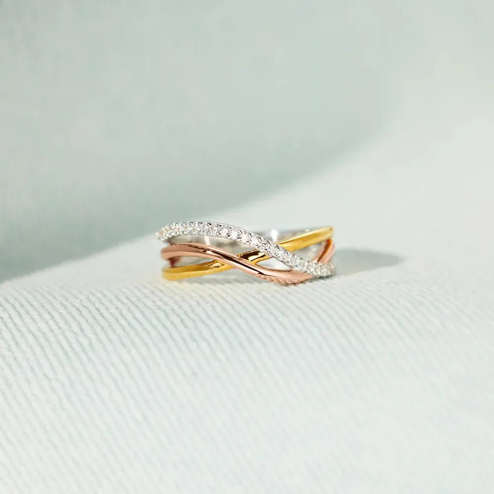 Intertwined trio diamond ring with gold and rose gold bands, accented with pave diamonds.