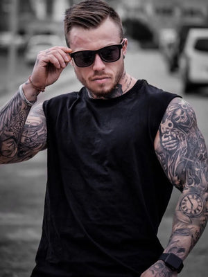 Black muscle-fit sleeveless tank top with crew neck, worn by a tattooed man.