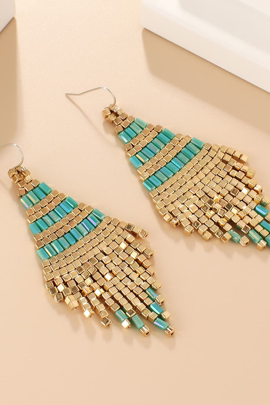 Turquoise and gold geometric beaded fringe earrings with a diamond shape.