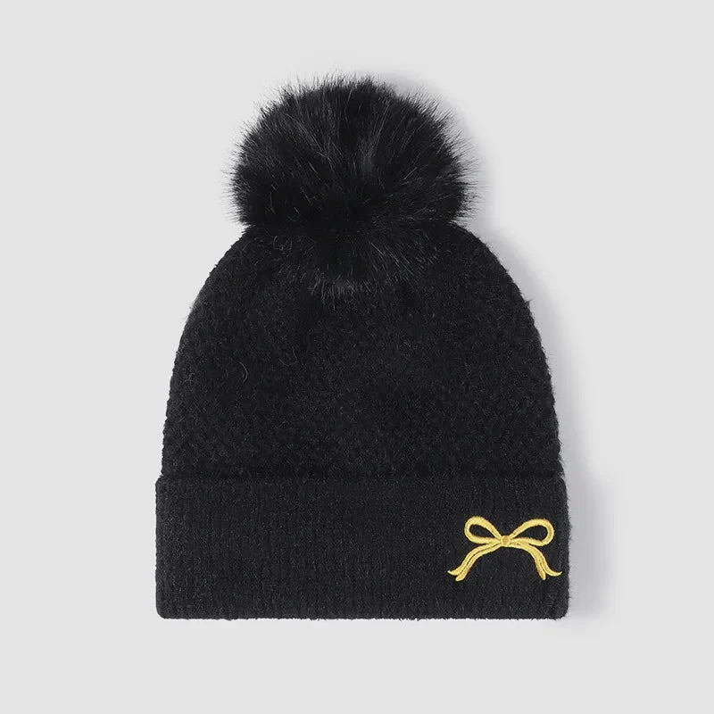 Black textured knit beanie with pom-pom and gold bow detail