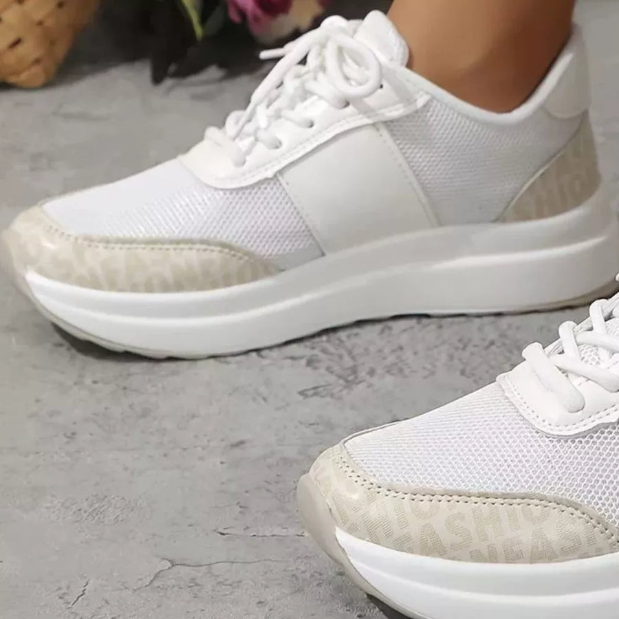 White lace-up sneakers with mesh and distinctive logo detailing on the sole.