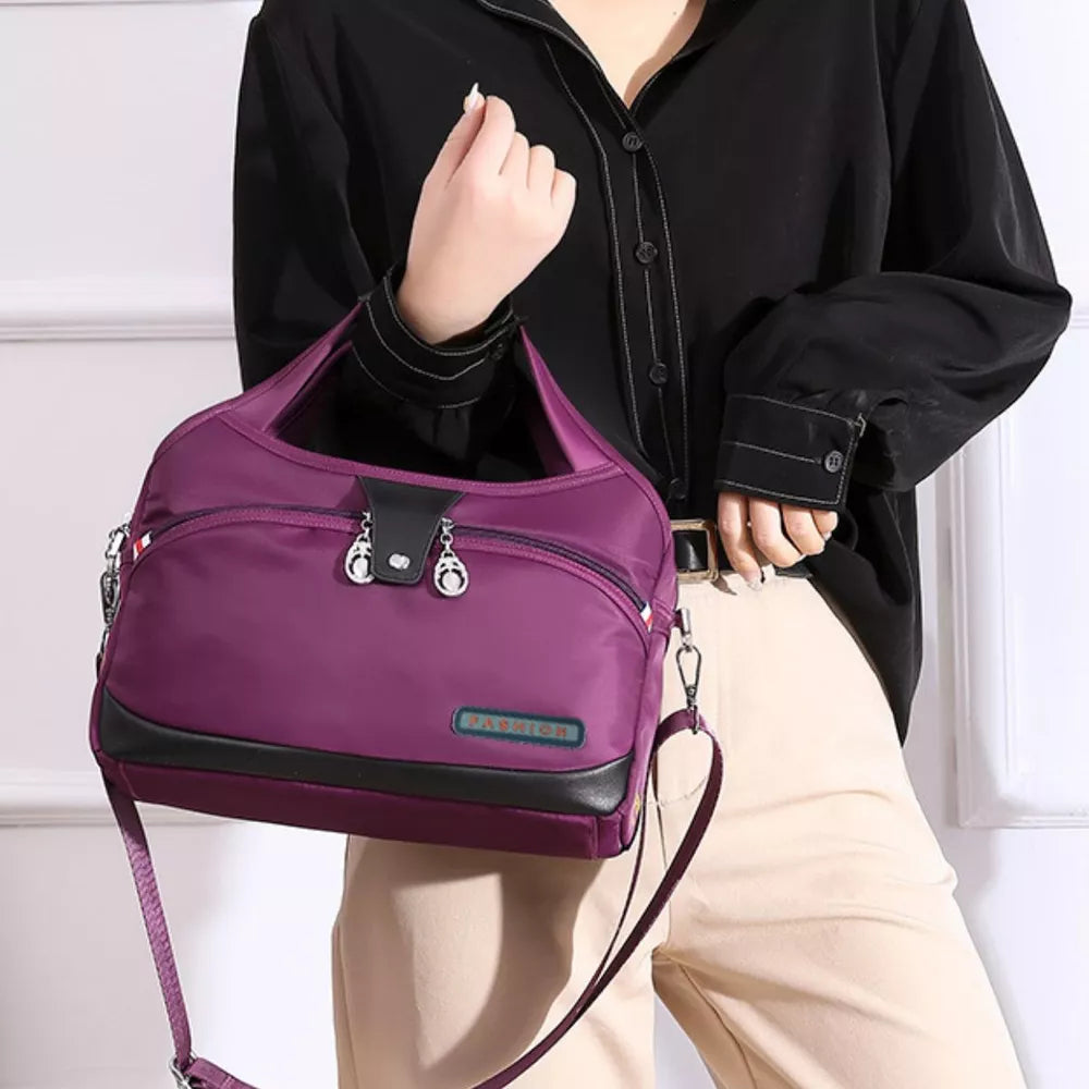 Spacious purple nylon tote bag with black trim and decorative charms.