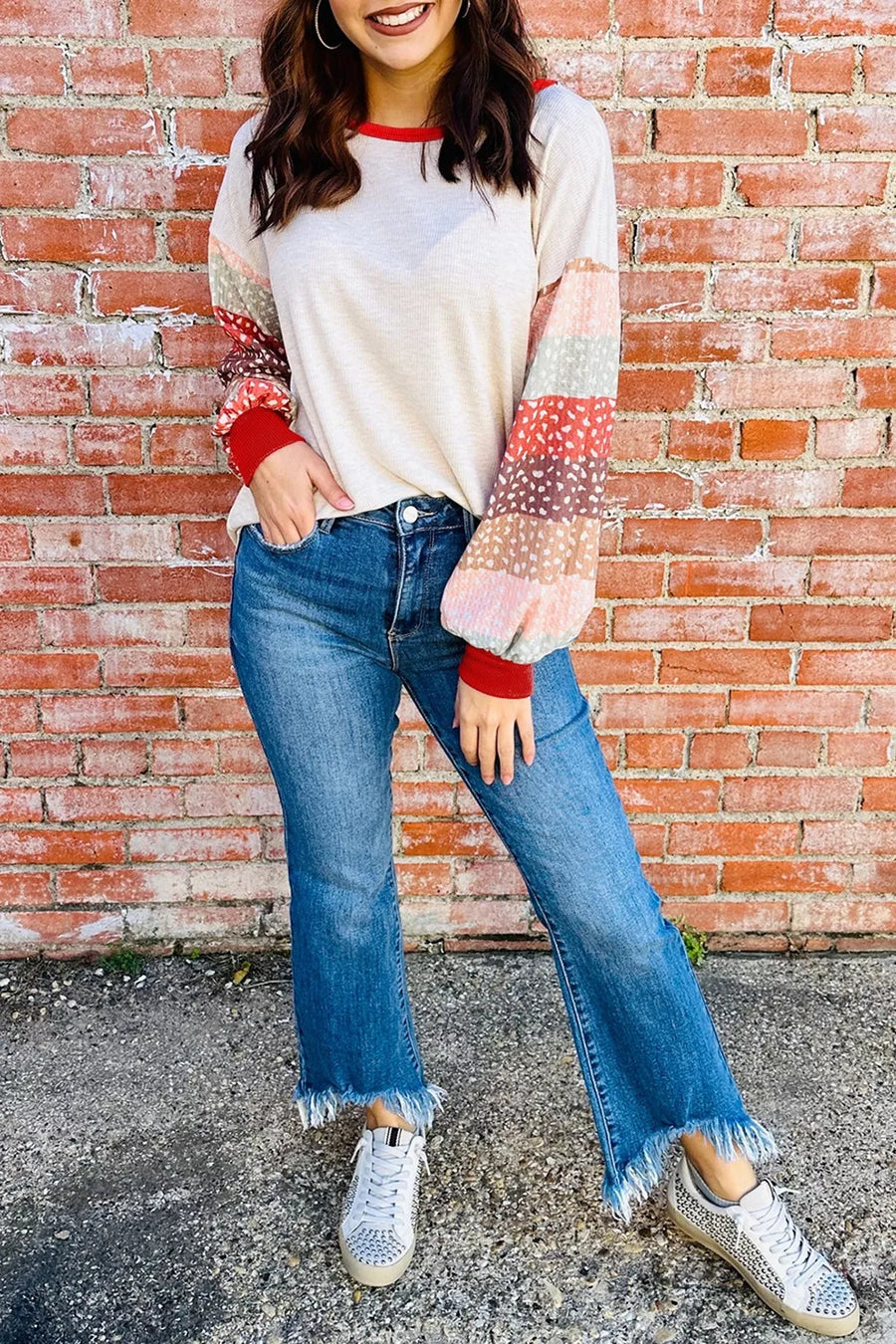 Cream top with multicolor striped puff sleeves and red trim, paired with frayed hem jeans.
