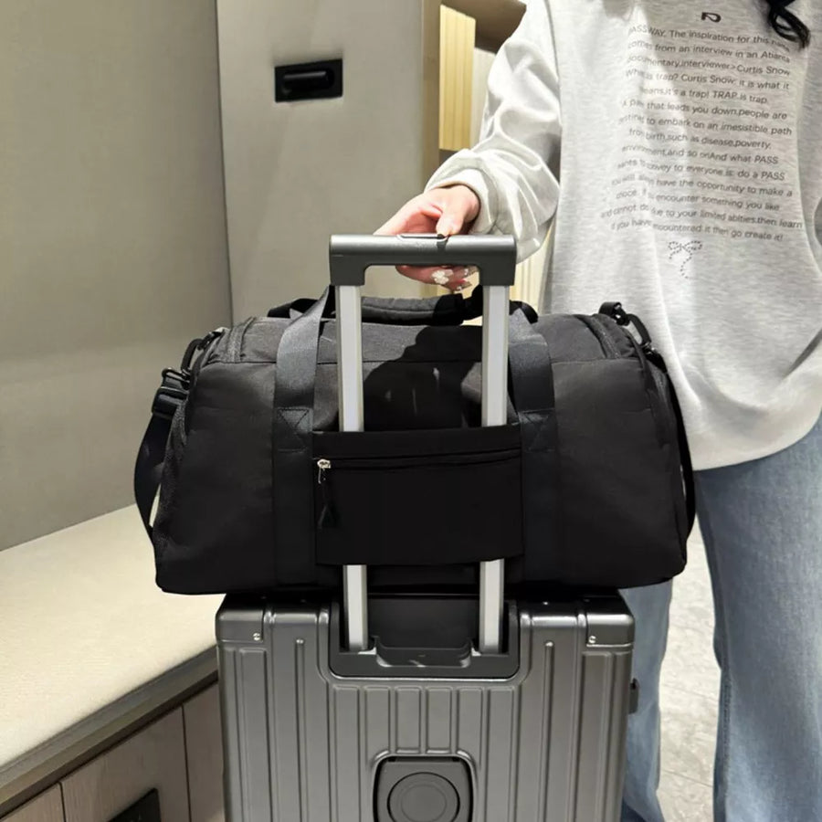 Black waterproof duffel bag with front zip pocket and trolley sleeve detail.