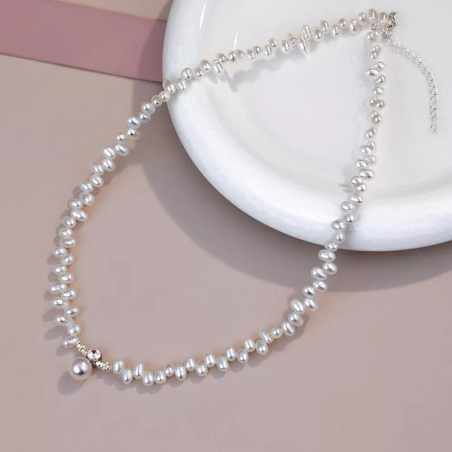 Lustrous irregular pearl pendant necklace with delicate silver accents and a single pearl drop.