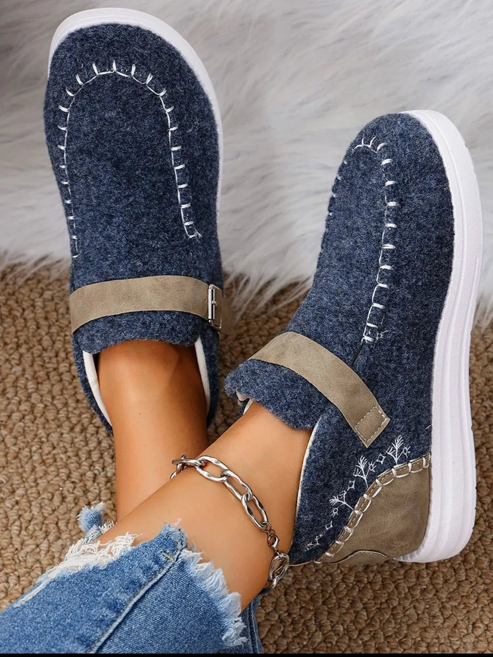 Dusty blue textured sneakers with white stitching detail, tan buckle strap, and embroidered accents.