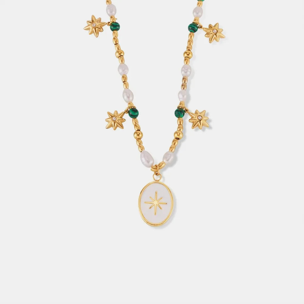 Gold celestial necklace with pearls, green beads, starburst charms and oval pendant.
