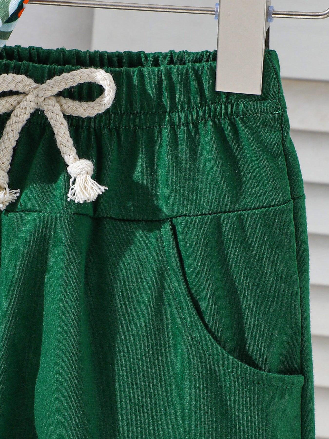 Dark green cotton baby shorts with drawstring and pocket detail.