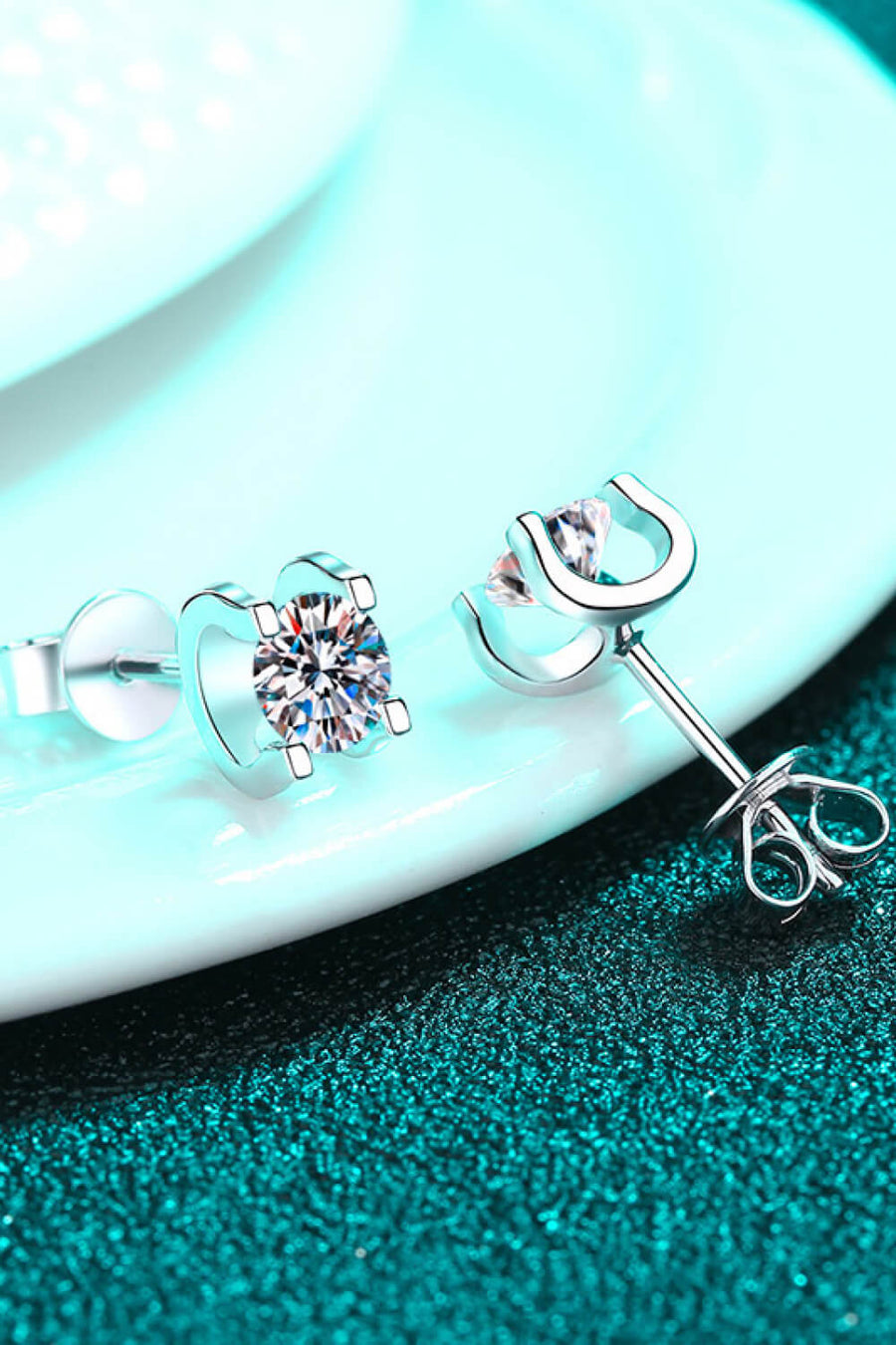 Silver moissanite stud earrings with sculpted heart and horseshoe settings.