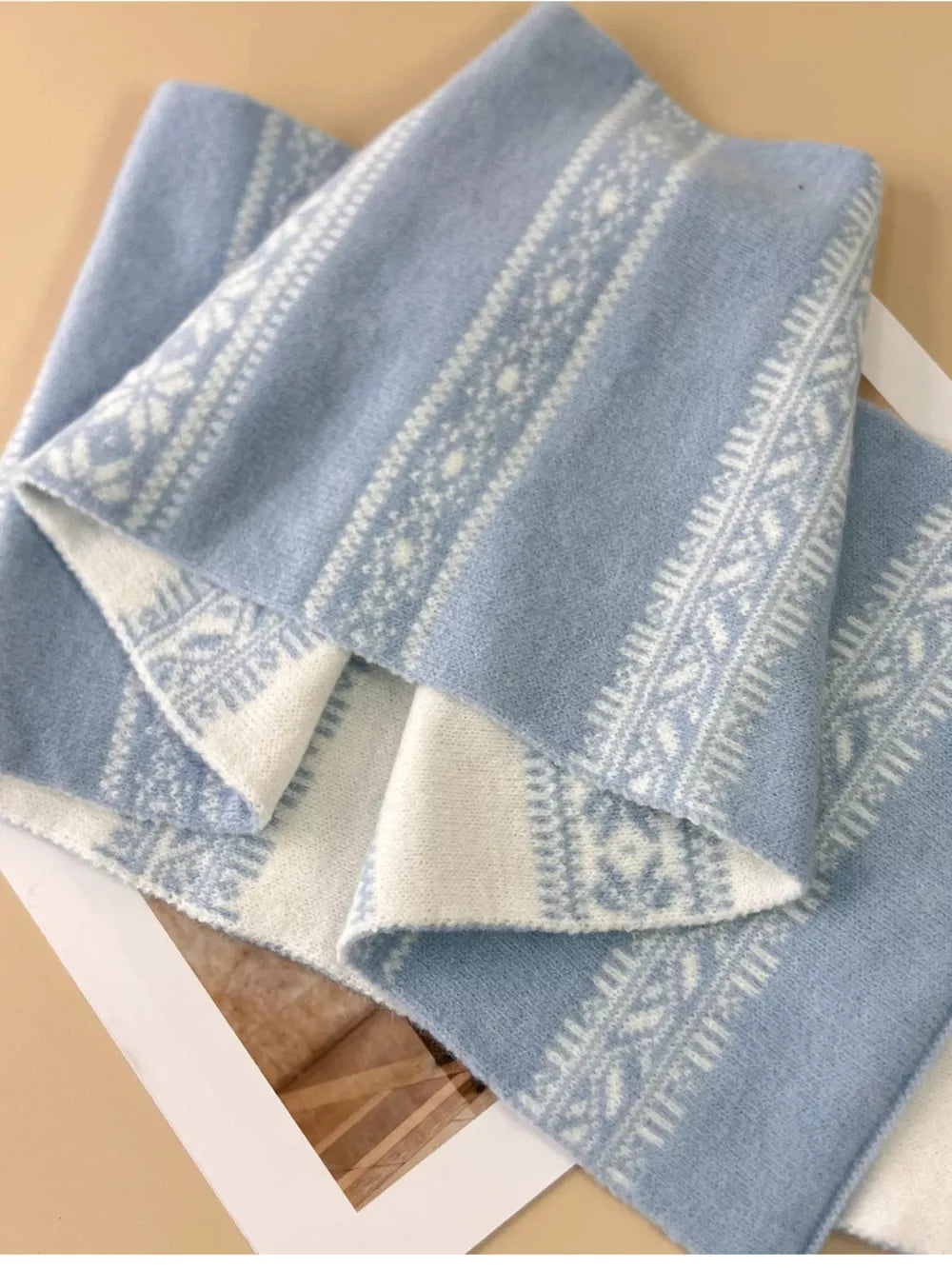 Sky blue wool blend scarf with reversible snowflake pattern and white trim.