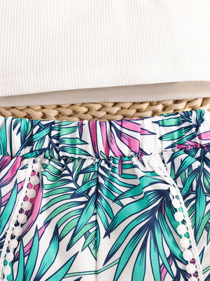 Baby floral shorts with white pom-pom trim and elasticated waist, paired with a white ribbed tank top.