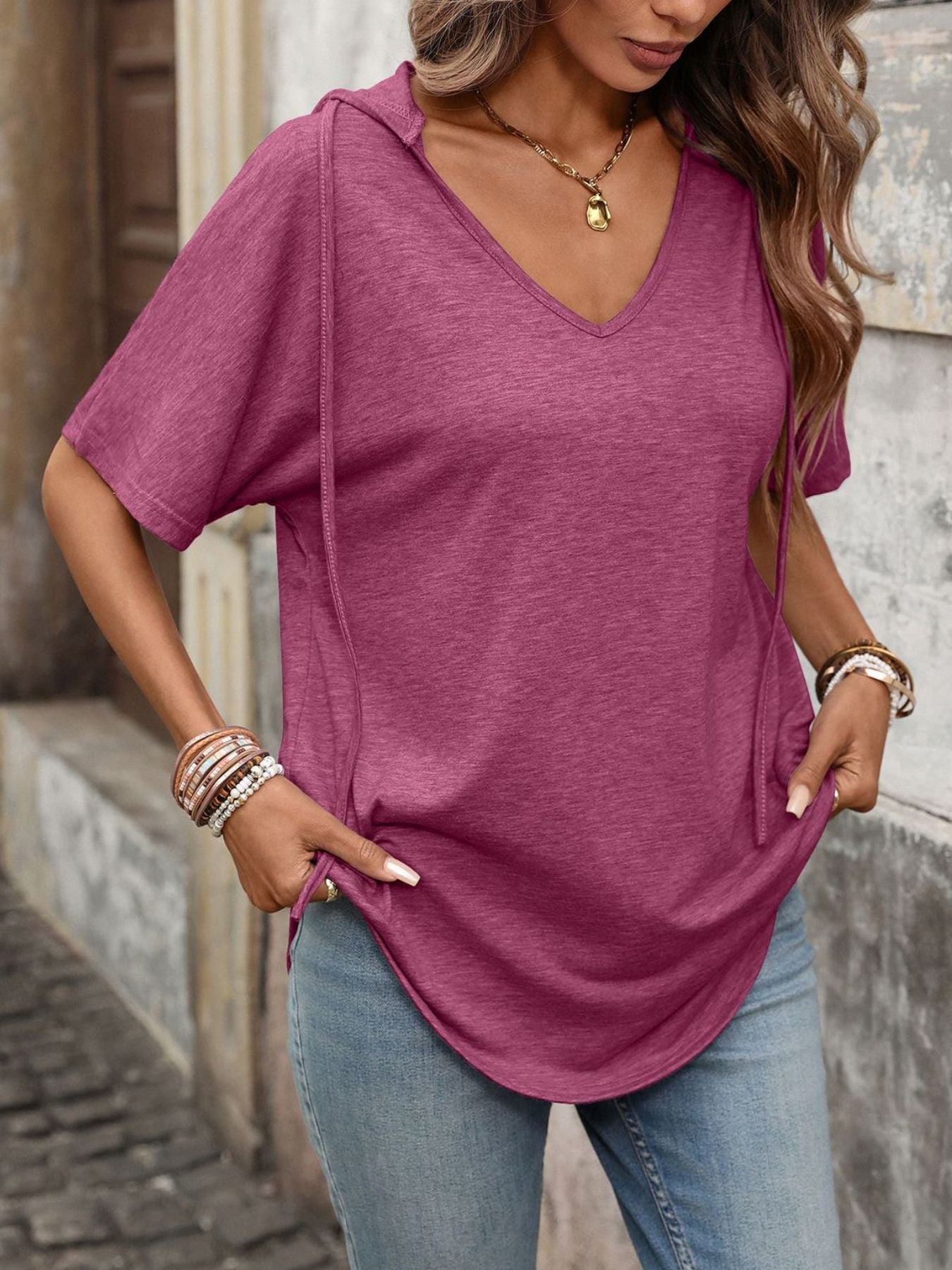 Burgundy hooded t-shirt with short sleeves and a V-neck, styled with jeans.
