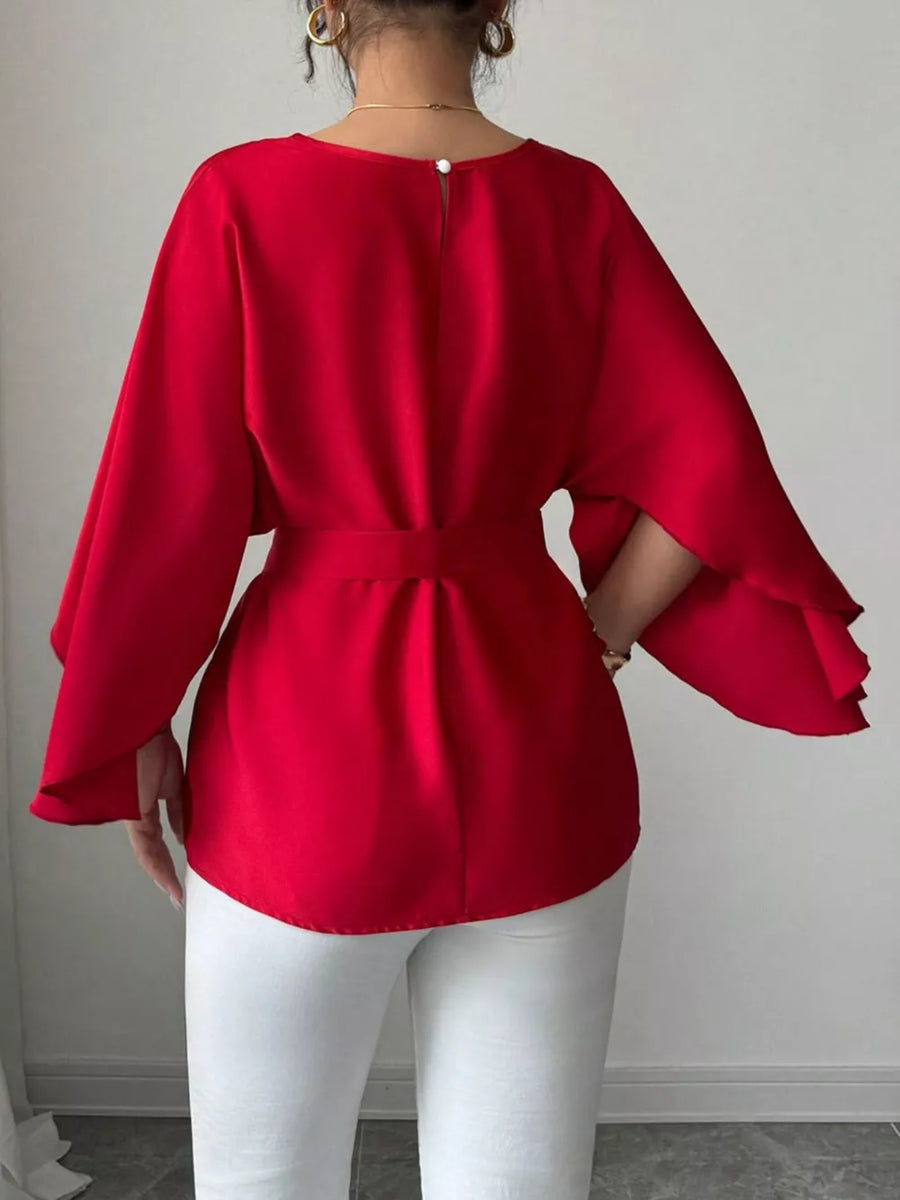 Red belted blouse with batwing sleeves and button closure at back neck.