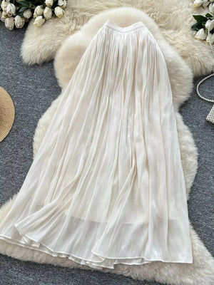 White pleated maxi skirt with flowing fabric and layered hem.