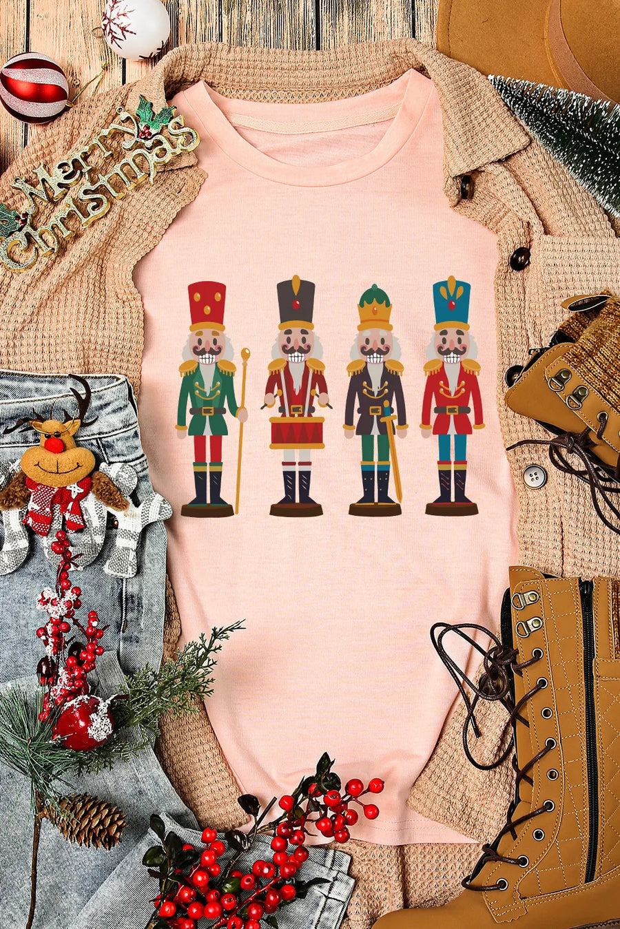 Blush pink t-shirt with a graphic print of four nutcracker soldiers in colorful uniforms.