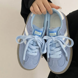 Pastel blue suede trainers with white signature stripes and laces.