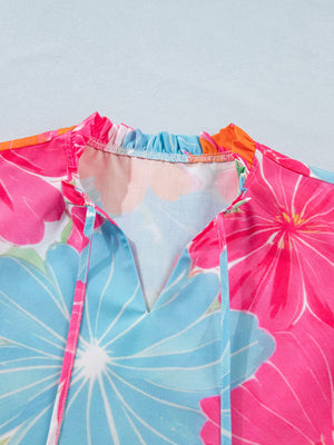 Tie neck blouse with bright floral print, ruffled collar, and V-neck with ties.