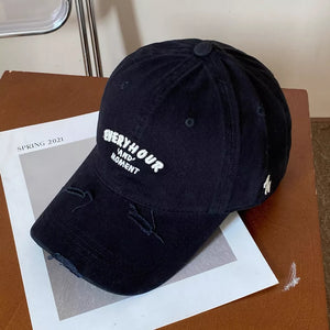 Black distressed baseball cap with embroidered text and distressed brim.