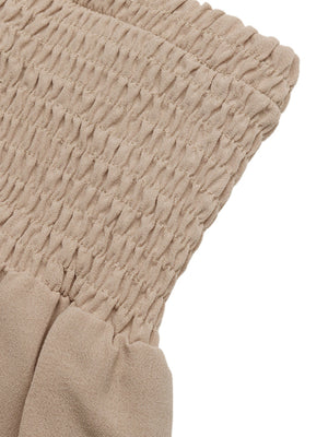 Smocked waist wide leg trousers in beige cotton, showing textured smocking detail.