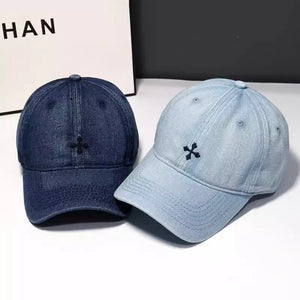Embroidered denim baseball hats in dark blue and light blue with a small black cross detail.