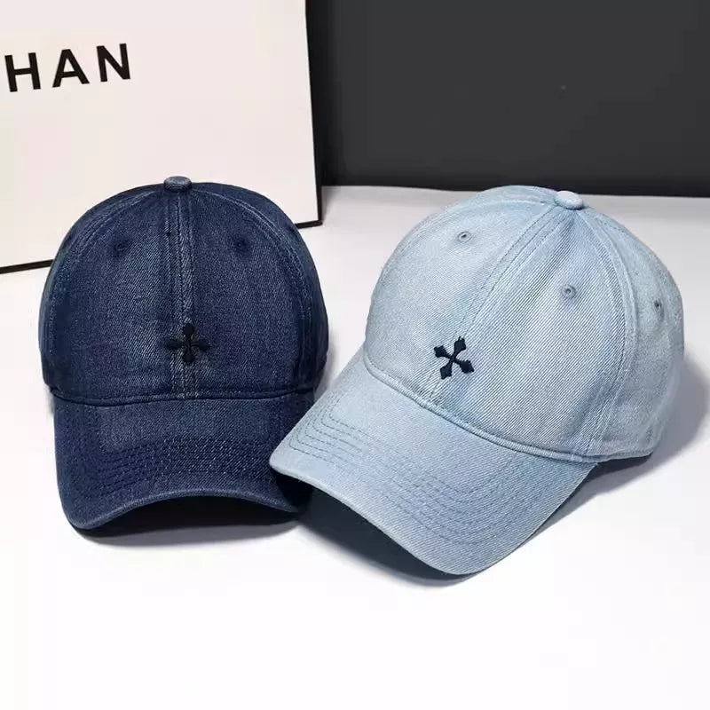 Embroidered denim baseball hats in dark blue and light blue with a small black cross detail.