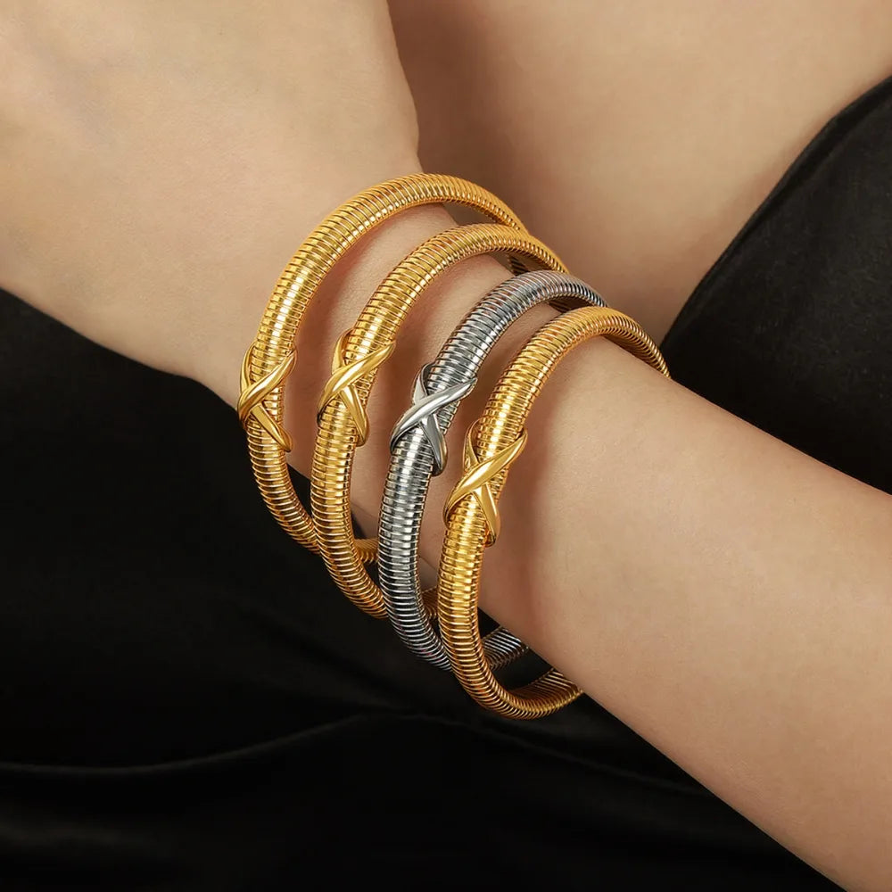Gold and silver ribbed X-detail bangles stacked on a wrist