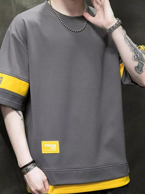 Men's grey oversized t-shirt with yellow contrast sleeve bands and a yellow patch detail.
