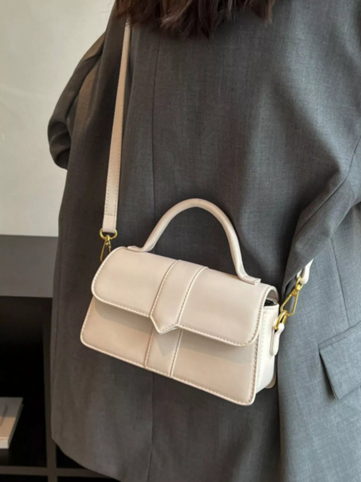 Chic small top handle bag in rice white with a flap closure and gold hardware.