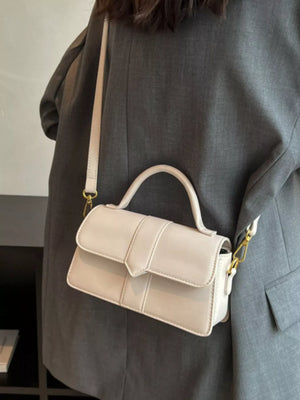 Chic small top handle bag in rice white with a flap closure and gold hardware.