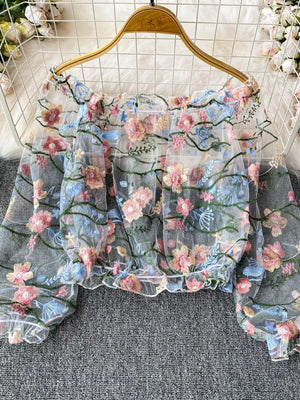 Sheer off-shoulder t-shirt with embroidered floral detail and ruffled hem.