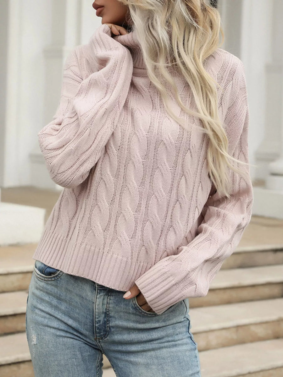 Pink cable knit turtleneck sweater with ribbed cuffs and hem.